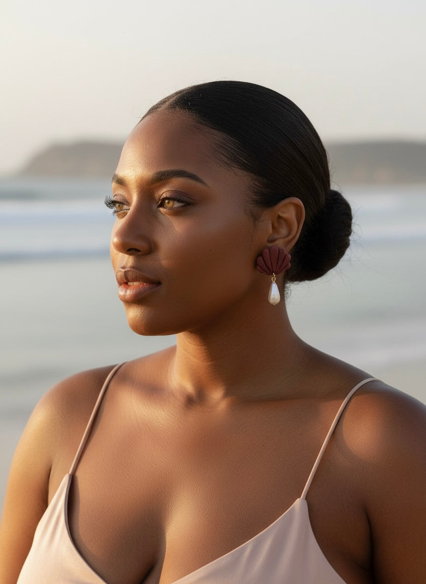 Woman with styled hair and earrings standing against a blurred natural background
